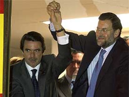 Rajoy alza la mano de Aznar en la ventana de la sede central del PP en Madrid la noche electoral.