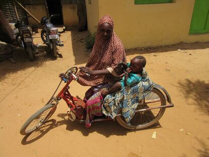 Sabuwa Mohamed y su pequeña Fatima Tasiu en la bicicleta adaptada por la que se desplazan por Bimi. Pese a haber sufrido la polio y haber perdido la movilidad de sus dos piernas, ha sido madre de tres hijos.