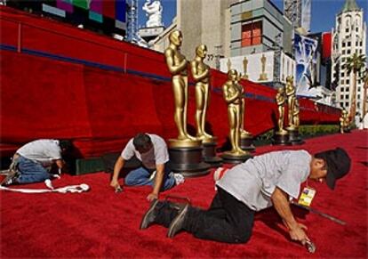 Unos operarios repasan los remates de la alfombra roja en el teatro Kodak.