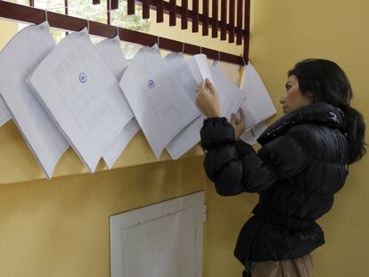 Una ciudadana consultan en las listas de un colegio electoral de Madrid.