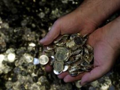 Un empleado de la Casa de la Moneda sostiene monedas de un euro. EFE/Archivo