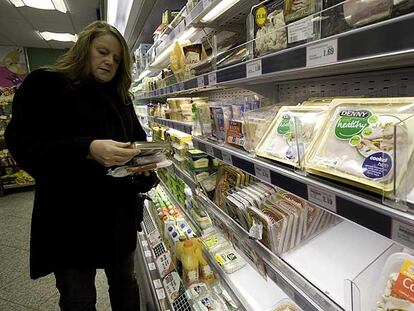 Una consumidora lee el etiquetado de bandejas de carne de cerdo en un supermercado de Belfast.