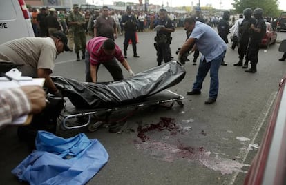 Forensics experts move the bodies of two police officers killed in Culiacán