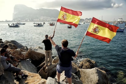 Dos hombres ondean la bandera española desde la costa de Algeciras, animando la protesta de los pescadores, frente al peñón de Gibraltar.