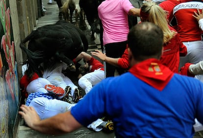 Los toros pasan por encima de varios mozos en la calle Estafeta, durante el cuarto encierro de los Sanfermines.