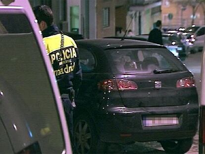 Un agente de la Policía permanece junto al vehículo bajo el cual estaba la bomba, en la calle Palomeras de Madrid.