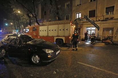 Los servicios de emergencia recogen los desperfectos de la ca&iacute;da de un &aacute;rbol sobre un coche.