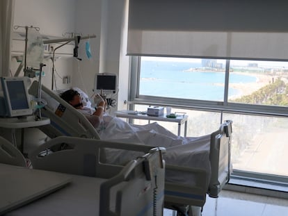 Un paciente con covid mira el móvil desde una habitación del Hospital del Mar de Barcelona, donde está ingresado
