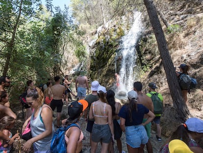 Numerosos turistas esperan su turno para refrescarse en una cascada en el río Chíllar, en Nerja (Málaga).