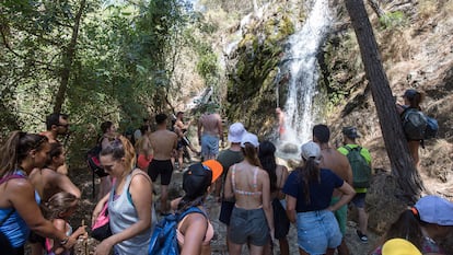 Numerosos turistas esperan su turno para refrescarse en una cascada en el río Chíllar, en Nerja (Málaga).