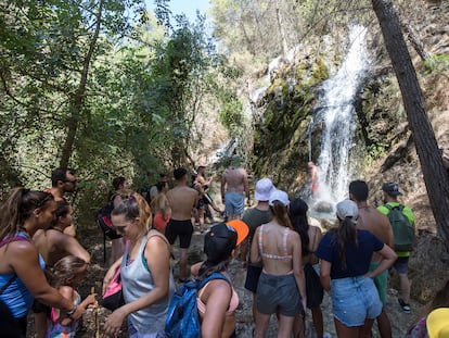 Turistas y veraneantes practican senderismo por el cauce del río Chíllar.