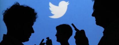 Usuarios miran sus móviles junto a un símbolo de Twitter.