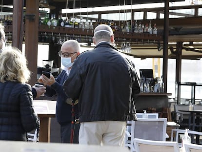 Los clientes muestran a un camarero su pasaporte Covid en un bar de Palma de Mallorca.