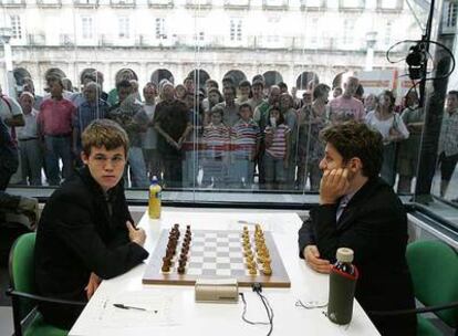 Magnus Carlsen y Levon Aronián aguardan a que comiencen las partidas. Detrás de la urna, un nutrido grupo de aficionados.