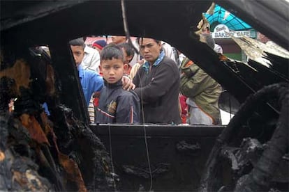 Un grupo de niños miran el interior de un coche abrasado tras los disturbios del decimocuarto día de huelga general en Katmandú. Al menos cuatro personas han muerto en el día de hoy tras la intervención de la policía contra los manifestantes en la ciudad de Chandragadi.