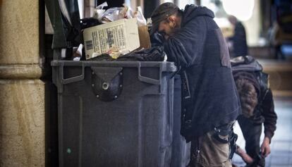 Un home busca menjar als contenidors d'un restaurant a Barcelona.
