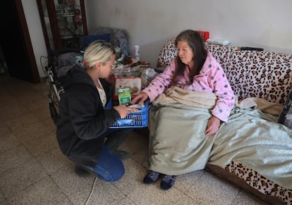 Soledad le lleva comida y bebida a María del Carmen, en la casa de esta en Massanassa. 