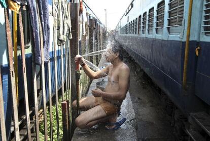 Um passageiro toma banho em uma estação de trem de Jammu, Índia.