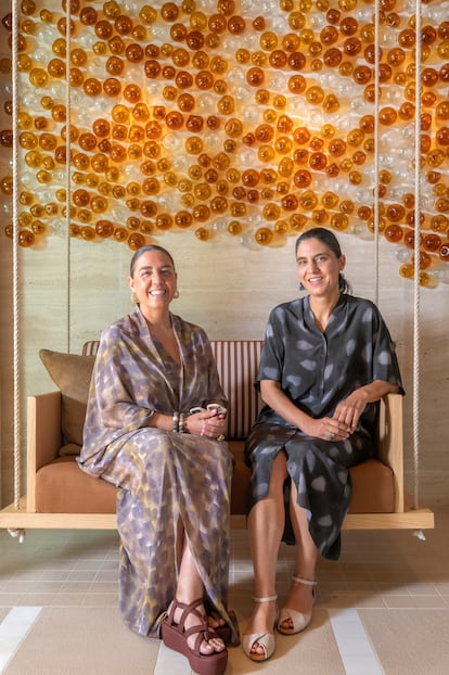 María Isabel y Alejandra Bordoy Bennàsar, galeristas y hermanas mellizas, a cargo de la colección de arte del hotel y fundadoras de la galería Art Aba Lab. En la foto, en un columpio con tapizado de Loro Piana, y en la pared una instalación de bolas de vidrio soplado de la centenaria casa mallorquina Gordiola.