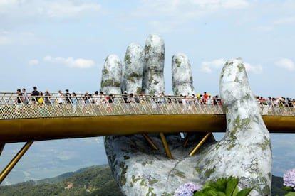 Varios turistas cruzan el nuevo puente Cau Vang (puente de oro).