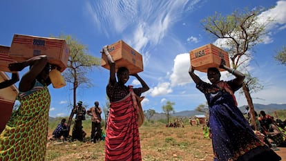 Mujeres de la tribu Dadinga llevan cajas de aceite durante la distribución de alimentos por el Programa Mundial de Alimentos.