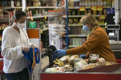 Una cajera atiende a una clienta en un supermercado durante el confinamiento.