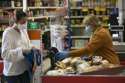 Una cajera atiende a una clienta en un supermercado durante el confinamiento.