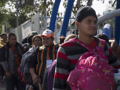 Integrantes de la caravana migrante esperan en fila para entrar al albergue temporal en Tijuana.