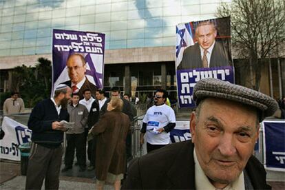 Varios afiliados del Likud acuden a un colegio electoral en Jerusalén con carteles de Netanyahu y Shalom.