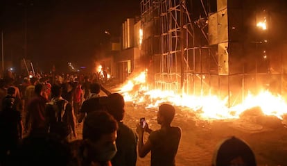 Manifestantes caminan junto a las oficinas en llamas de partidos políticos, este jueves en Basora.