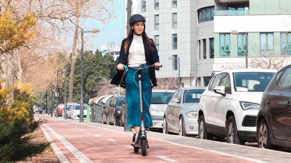 Una mujer pasea por un carril bici con el patinete eléctrico de Cecotec Bongo D20.