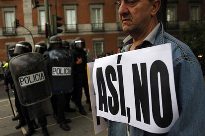Un hombre sujeta unas pancartas durante las cargas policiales en la plaza de Neptuno, Madrid.