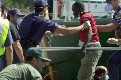 En la imagen, un Policía Nacional ayuda a los indocumentados a salir del pesquero.