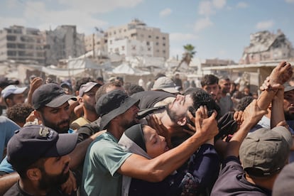 Un grupo de gazatíes carga el cuerpo de una persona que murió cuando buscaba ayuda humanitaria, este jueves en Gaza.