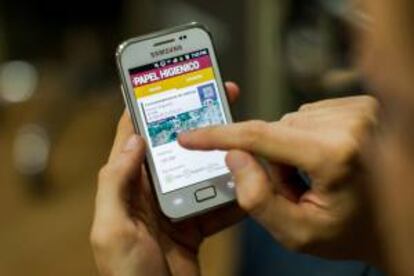 Un hombre sostiene un teléfono móvil mientras usa la aplicación "Abastéceme", este 7 de junio, en Caracas.