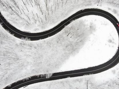 Un coche conduciendo por una carretera que atraviesa un bosque nevado en Budapest (Hungría).