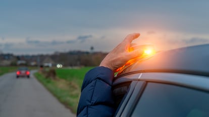 Una persona poniendo la baliza v16 en el techo de su coche durante un viaje en carretera.