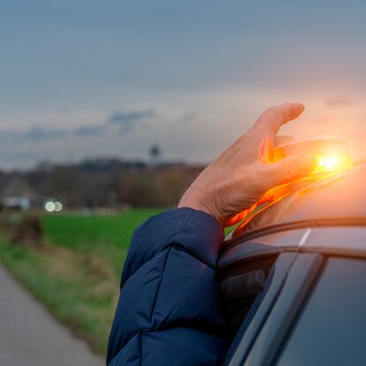 Una persona poniendo la baliza v16 en el techo de su coche durante un viaje en carretera.