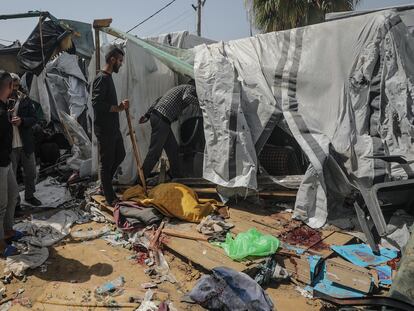 Ciudadanos palestinos inspeccionan un refugio destrozado por ataques israelíes cerca del hospital de Al Aqsa en el sur de Gaza este domingo.