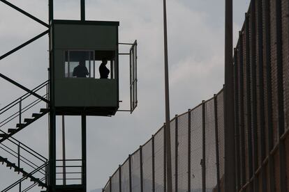 Dos miembros de la Guardia Civil vigilan, desde una torre de control en el puesto fronterizo de Melilla, la valla que separa a España de Marruecos.