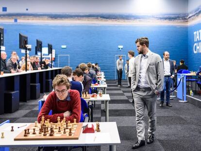 Magnus Carlsen pasea por la sala de juego en Wijk aan Zee durante su partida de este lunes; en primer plano, el español David Antón, participante en el Torneo B