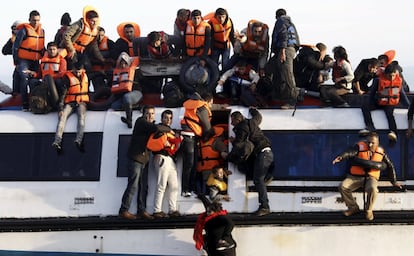 Refugiados e inmigrantes tratan de salir del barco mientras este se hunde frente a la isla griega de Lesbos.