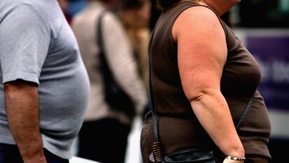 Two people living with obesity walk down a street in Glasgow, Scotland.