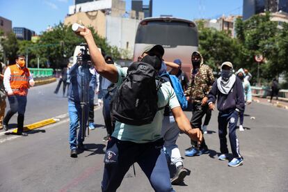 manifestante lanza un objeto a la policía durante una marcha por el caso Ayotzinapa