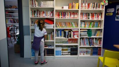 Una ni&ntilde;a recoge un libro en un centro educativo. 