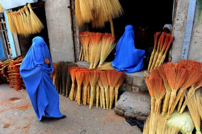 Compradoras afganas buscan escobas en una tienda de carretera en Herat.