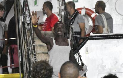 Un hombre saluda mientras desembarca del 'Open Arms' en la isla siciliana de Lampedusa (Italia). Un fiscal italiano ordenó la captura del barco humanitario y la evacuación inmediata de más de 80 migrantes a bordo, poniendo fin a las escenas del martes donde 15 personas saltaron por la borda, en un intento desesperado por escapar de las condiciones deterioradas en el barco.