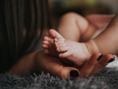 Una madre sujeta los pies de su recién nacido.