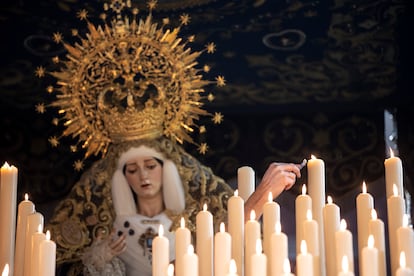 Un hermano de la cofradía de Jesús El Rico y María Santísima del Amor, enciende una vela del trono de la Virgen, este miércoles de la Semana Santa en Málaga. 

