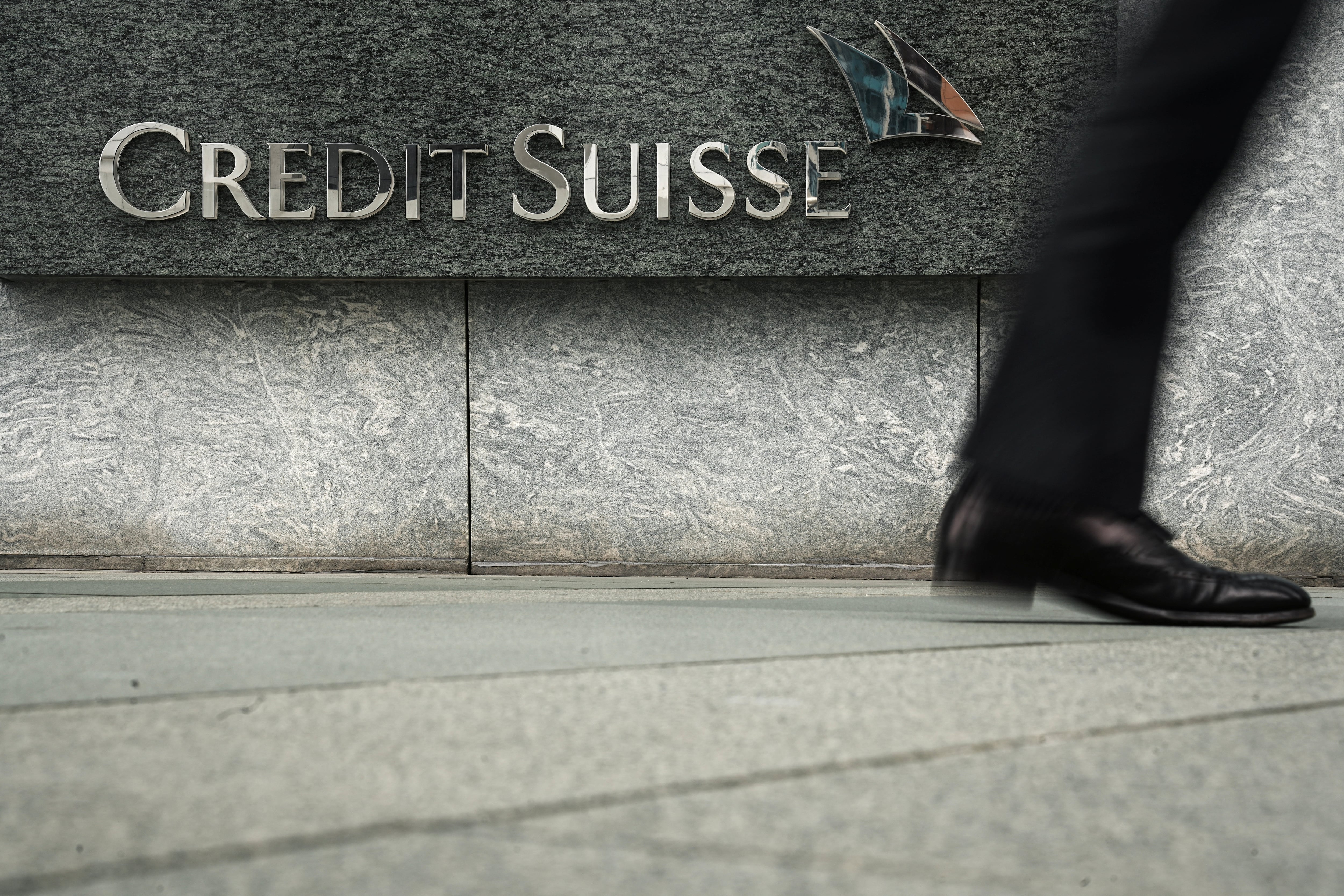 Una persona pasea junto a unas oficinas de Credit Suise en Hong Kong.